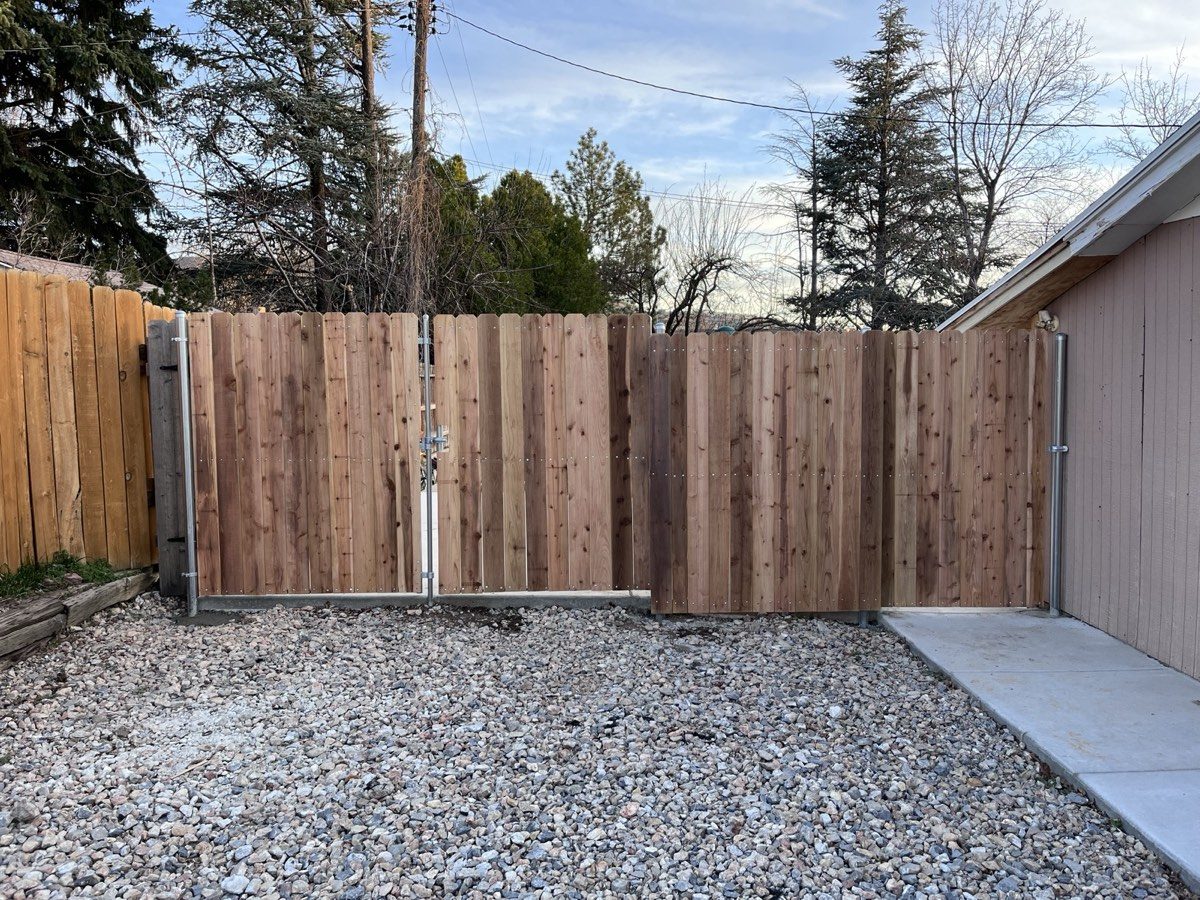 Cedar privacy fence with a double drive gate across a gravel driveway in Bluffdale, UT