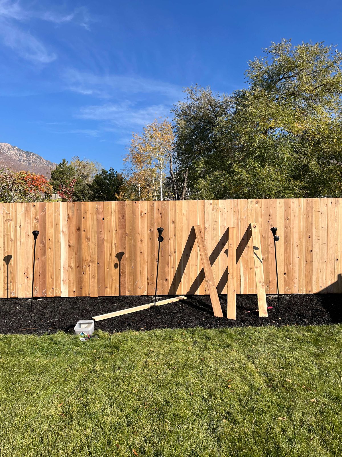 New cedar fence during installation with braced boards and posts set in concrete, Salt Lake Valley