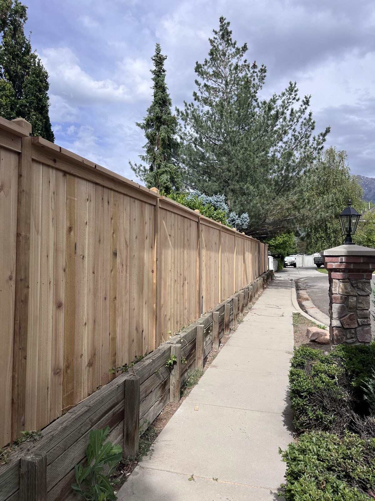Capped cedar privacy fence along a sidewalk in Millcreek, Utah