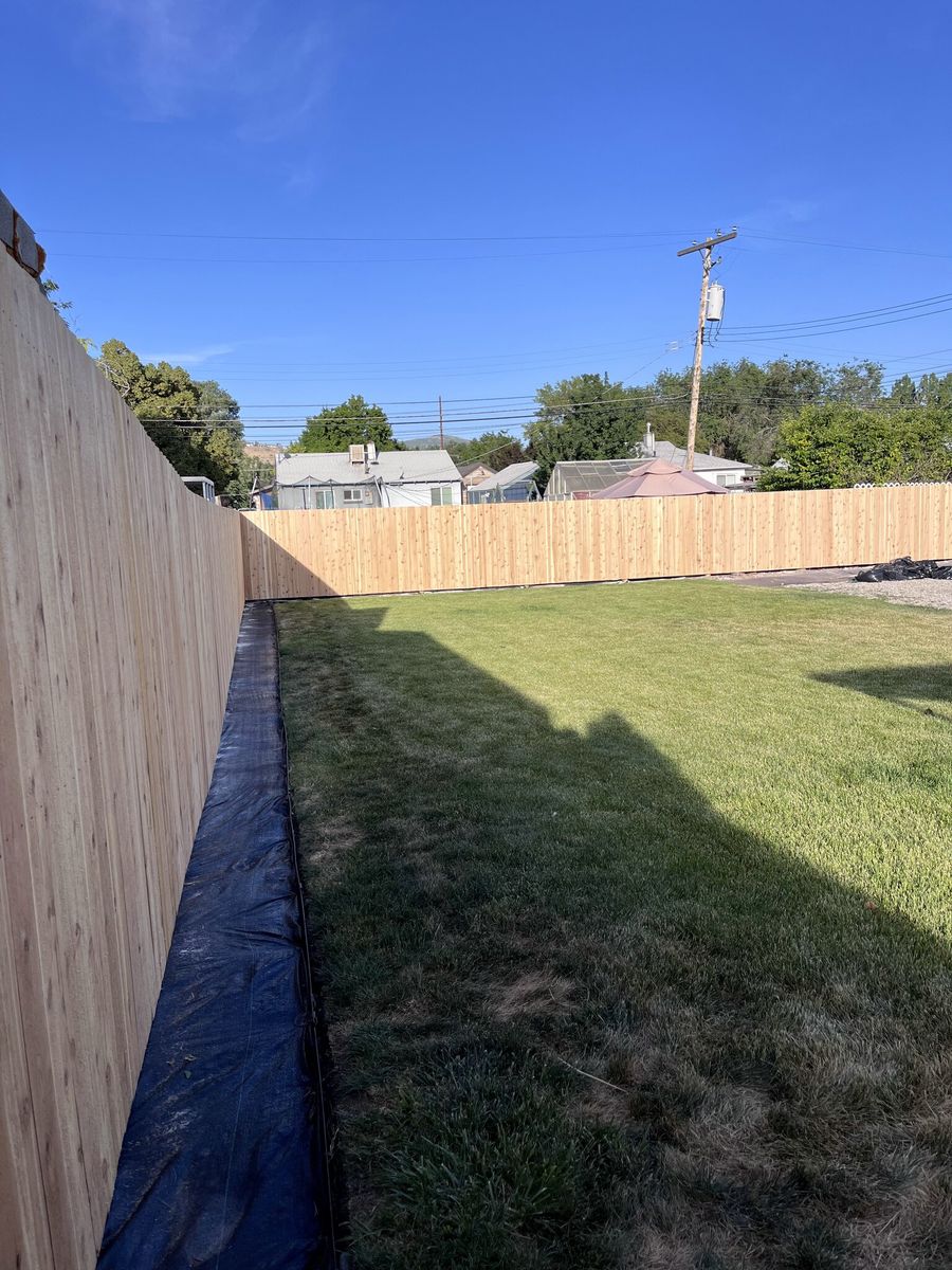 Cedar privacy fence along the side of a grass backyard in West Valley City, UT
