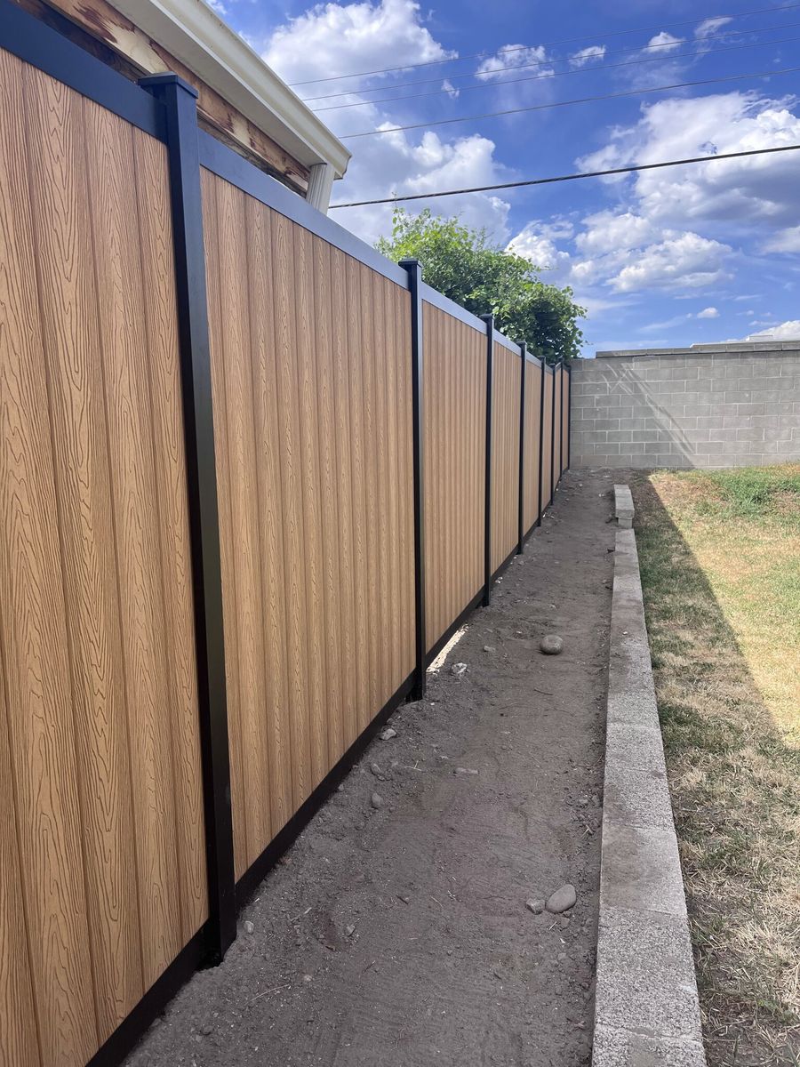 Close view of a woodgrain composite privacy fence with black posts in Draper, UT