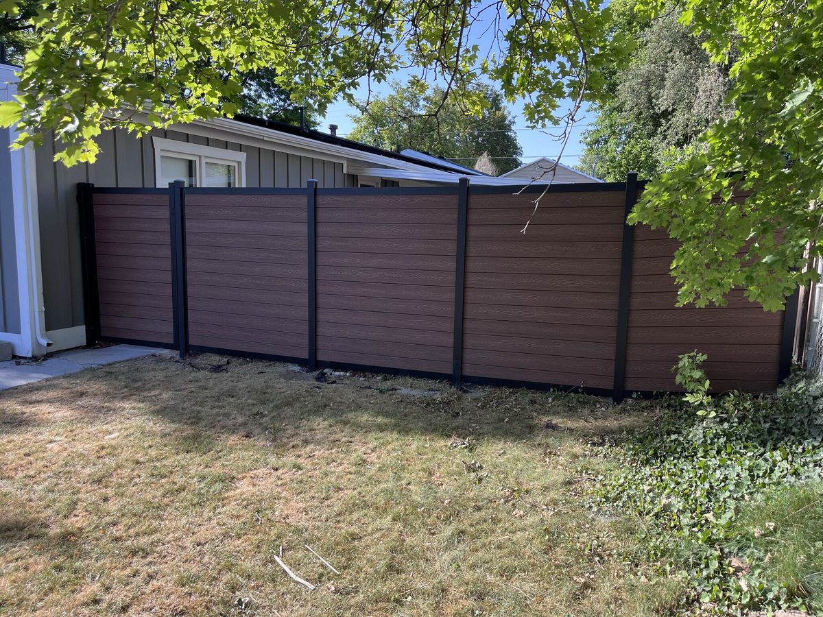 Dark composite privacy fence with black posts along a side yard in South Jordan, UT