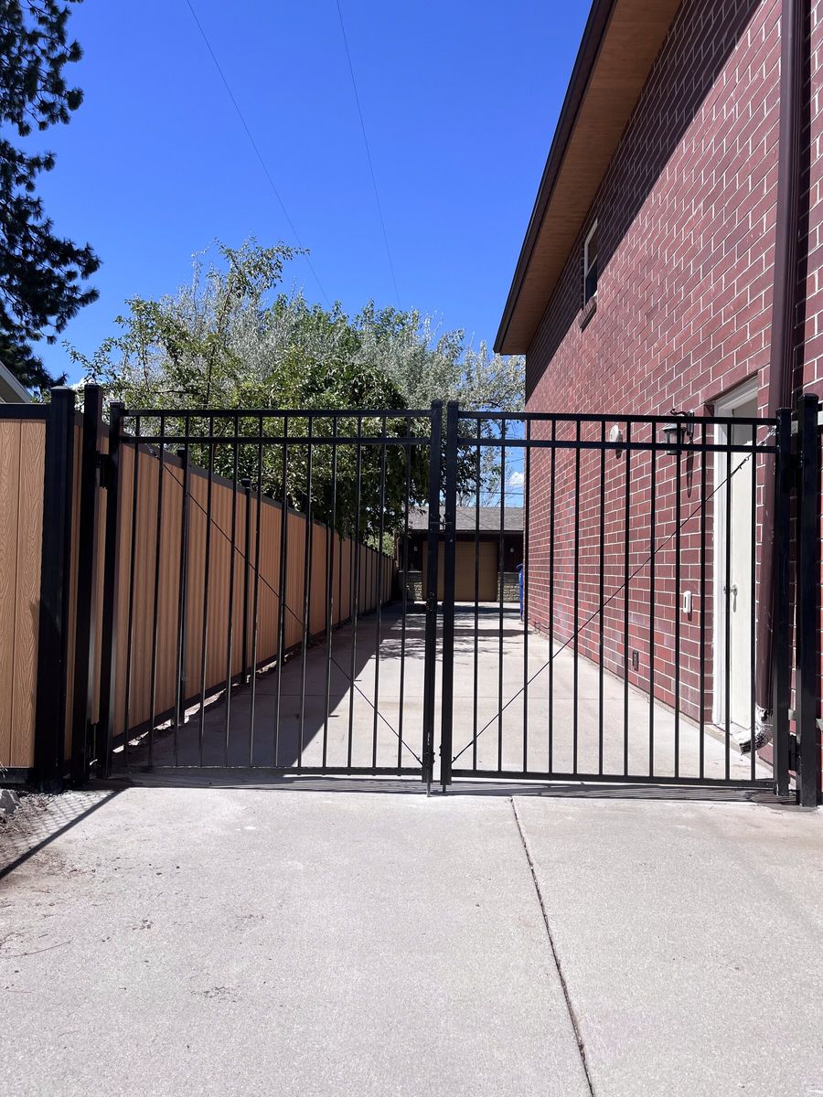 Black ornamental iron gate beside a red brick home in the Salt Lake Valley