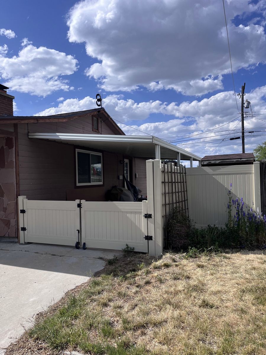 Tan vinyl privacy fence and gates beside a driveway in Holladay, UT