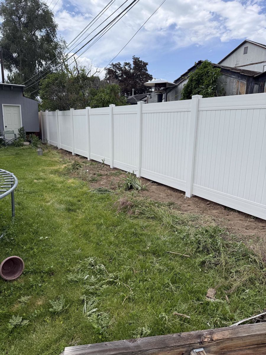 White vinyl privacy fence along a sloped backyard in Murray, UT
