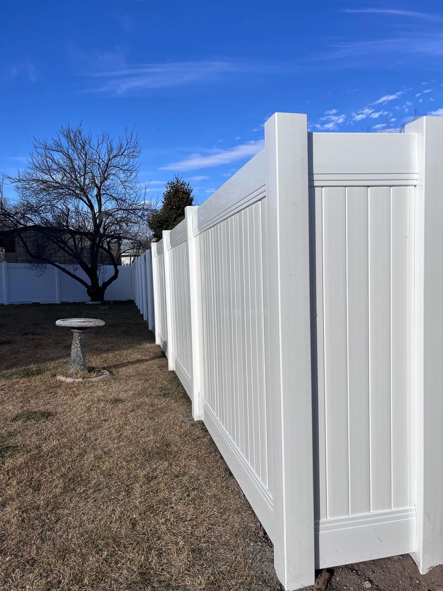 White vinyl privacy fence turning a corner around a backyard with a birdbath in West Valley City, UT