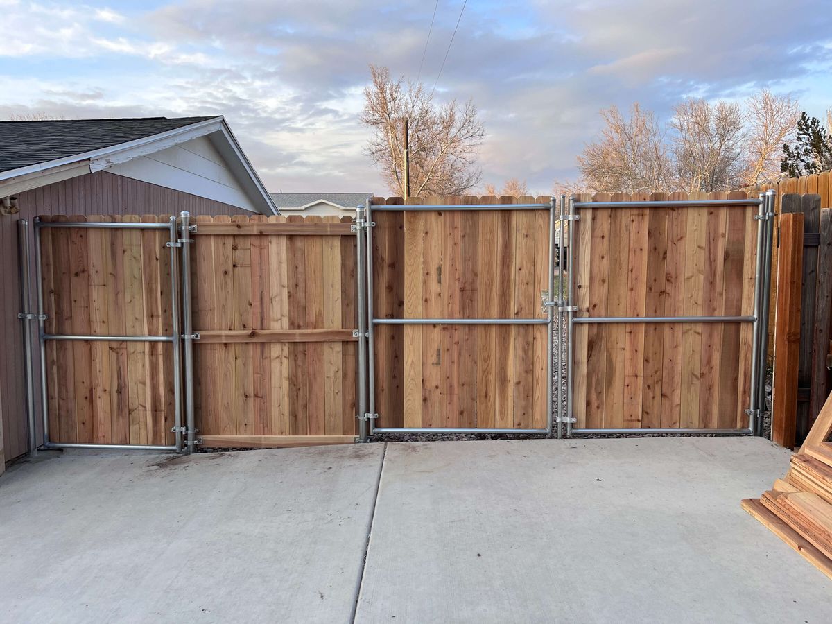 Wood privacy fence with a double drive gate in metal frames across a concrete driveway in Herriman, UT
